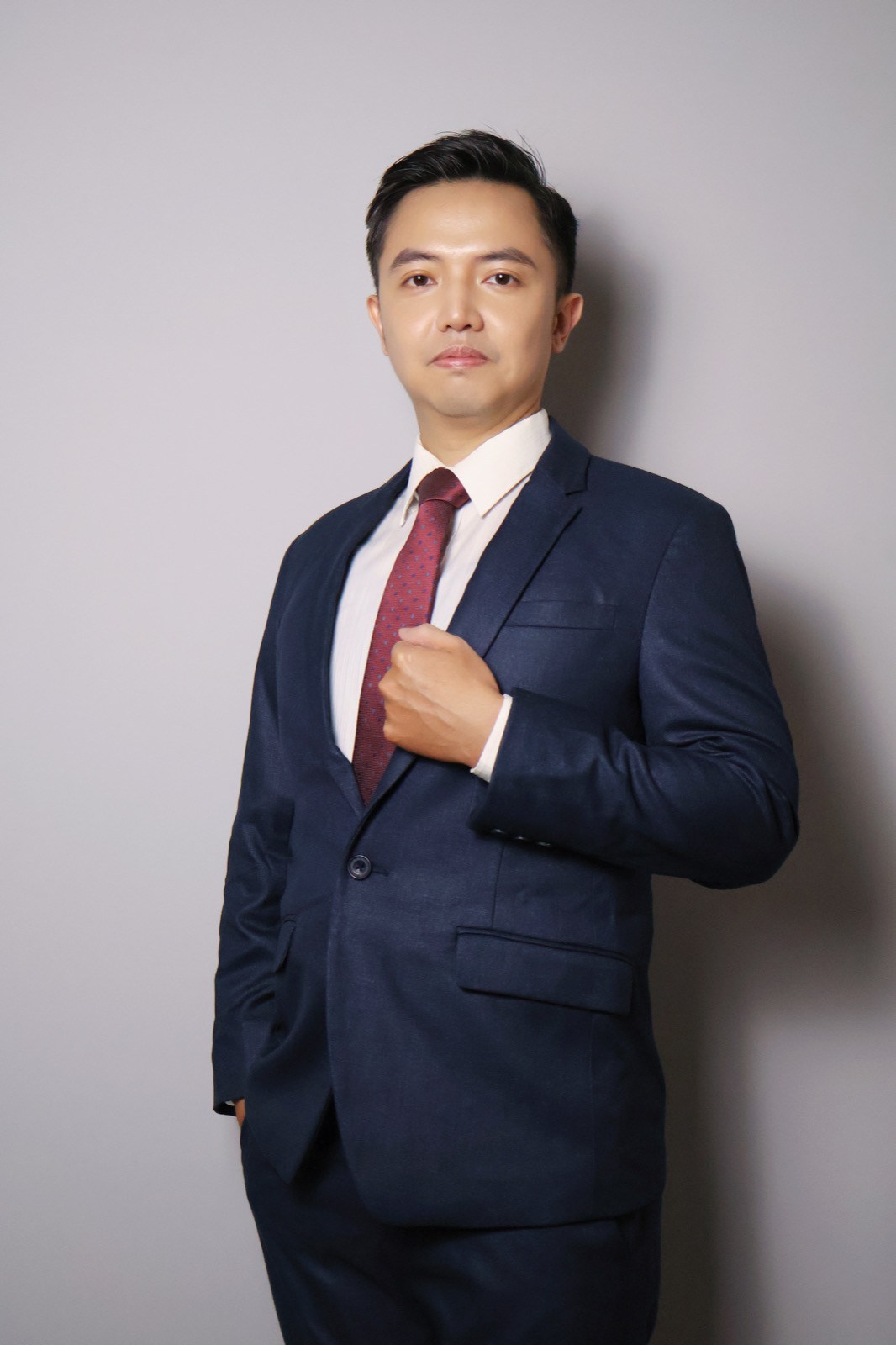 謝秉舟深色西裝形象照，整理領帶